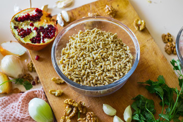 Grated, mixed and cut walnuts in glass bowl. Ingredient for Georgian traditional appetizer food - pkhali. Preparation process with garlic, pomegranate, cilantro, onion.