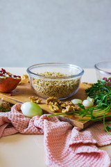 Grated, mixed and cut walnuts in glass bowl. Ingredient for Georgian traditional appetizer food - pkhali. Preparation process with garlic, pomegranate, cilantro, onion.