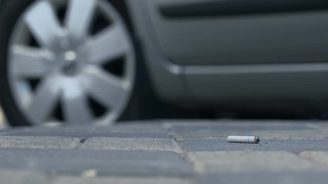 Driver throwing stub of cigarette on pavement, air pollution, dirty sidewalk