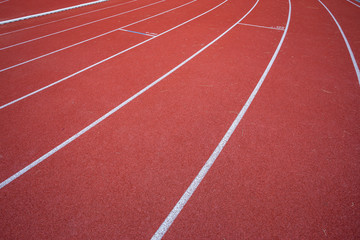 White lines of stadium and texture of running racetrack red rubber racetracks in outdoor stadium are 8 track and green grass field,empty athletics stadium with track.
