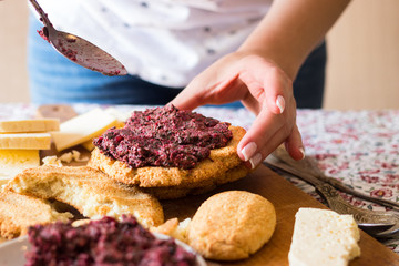 Woman hand spreads beetroot pkhali on mchadi - traditional Georgian cornbread traditionally eaten with lobio, suluguni cow cheese. raw vegan vegetarian healthy food