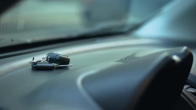 Man putting car keys on dashboard, driver leaving parked auto opened, car theft