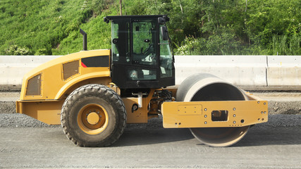 Yellow road roller at road construction and nature background