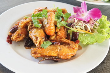 Fried shrimps with tamarins and fried dried chili sour and sweet sauce decorate with vegetables on white ceramic dish ready for serve