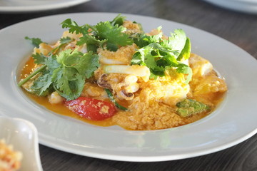 Squid stirred with York egg sauce and mix with tomato , onion and coriander on dish ready to serve