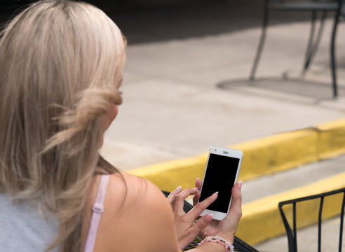 Blonde haired woman using a touch screen smart phone.