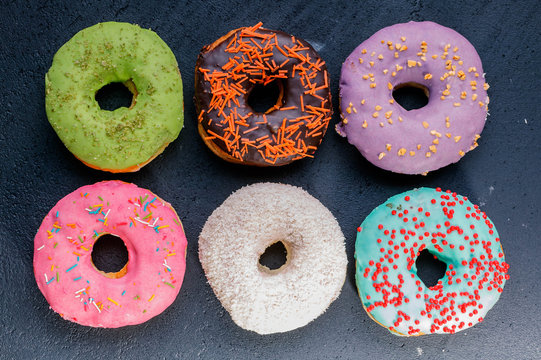 Donuts with a colorful icing on a dark background. Top view