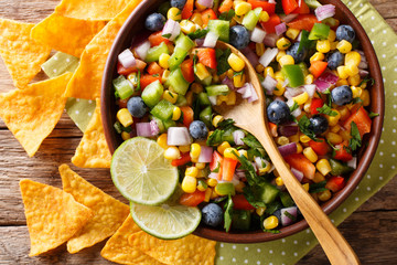 Spicy salsa from corn, blueberries, jalapeno pepper, bell pepper and onions is served with nachos...