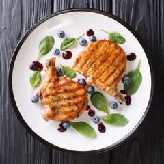 Barbecue food: grilled pork steak with ribs with fresh blueberry sauce and spinach closeup on a plate. top view