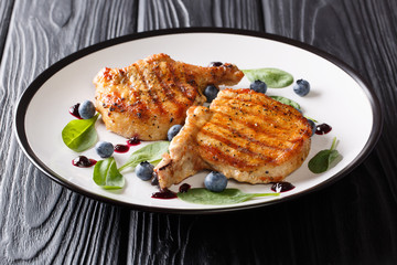 Delicious healthy food: grilled pork steak with ribs with fresh blueberry sauce and spinach closeup on a plate. horizontal