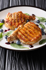 grilled pork tenderloin steak served with blueberry sauce and baby spinach close-up on table. vertical