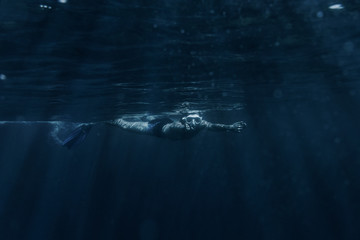 Man swimming underwater surface.