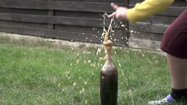 A little boy doing an experiment with soda in which there's an eruption  of the liquid from the top of the bottle.