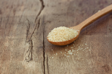 Natural brown sugar or no bleach sugar on wooden spoon put on wood table in side view with copy space. Sweet seasoning for good health concept. Ingredient prepared for cooking bakery and beverage.