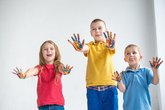 Three smiling kids with colourfull hands on white background