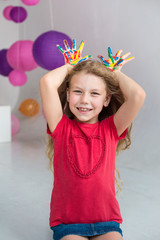 Little happy girl with painted colored hands shows bunny years on birthday party