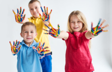 Three smiling kids with colourfull hands on white background
