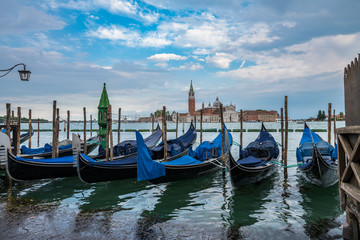 Fototapeta na wymiar Gondolas moored by Saint Mark square with San Giorgio di Maggiore church on blurry background in Venice, Italy
