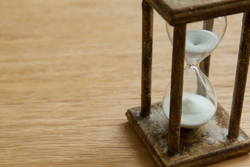 Hourglass on the Oak table as time passing concept for business deadline, urgency and running out of time.