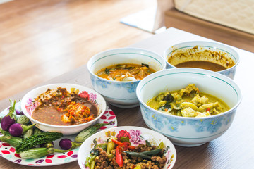 The poor eat a cup of spicy chili paste with vegetables and wild curry on a wooden table.