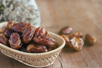 Khalas date palm on wooden basket in side view with copy space on wood table for background. Dates fruit is food for Ramadan or medjool. Delicious dried fruit with sweet taste and have high fiber.