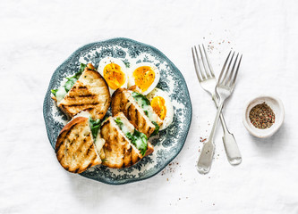 Healthy breakfast or snack - boiled farm eggs, spinach, grilled cheese sandwiches on light background, top view