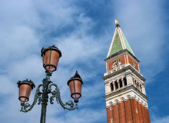 Fototapeta na wymiar The bell tower of San Marco Campanile and the famous Venetian street lamp. Campanile located on St. mark's square in front of San Marco Cathedral. Venice, Italy