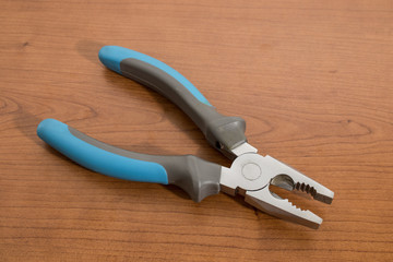 Tools, blue pliers on a walnut table