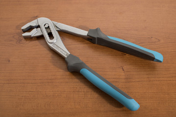Tools, blue pliers on a walnut table