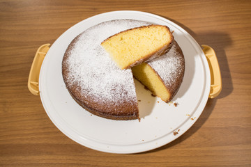 Slice of a delicious cake with powdered sugar on a wood table