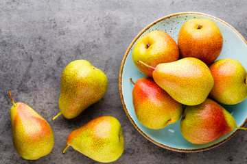 Fresh bio pear with leaves on the plate. Gray stone table.