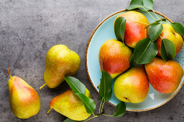 Fresh bio pear with leaves on the plate. Gray stone table.