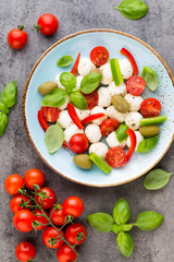 Delicious caprese salad with ripe cherry tomatoes and mini mozzarella cheese balls with fresh basil leaves.