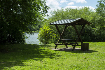 Summer arbor on the green meadow near lake.