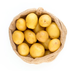 Sack of fresh raw potatoes on wooden background, top view