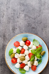 Delicious caprese salad with ripe cherry tomatoes and mini mozzarella cheese balls with fresh basil leaves.