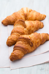 Tasty buttery croissants on old wooden table.