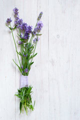 bunch of blooming lavender branches on a white painted wooden background with copy space, vertical