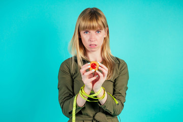 blonde woman keeps cookie in hand in studio on blue background . concept of rejection of flour products