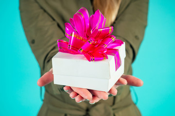 blonde woman keeps gift box in hand in studio on blue background