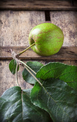 Organic red apple branch arrangement with green leaves on rustic wooden box in studio