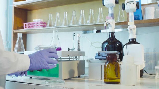 Top view. Chemical analysis laboratory. Close up hands of the scientist putting the funnel in the flask standing on the heating device