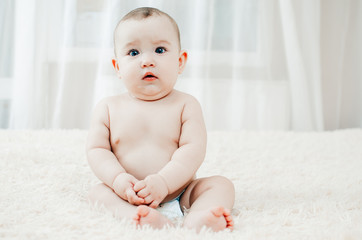 little charming girl sitting on the bed in the bright bedroom