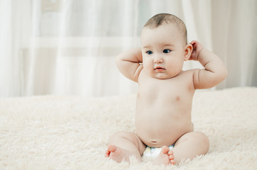 little charming girl sitting on the bed in the bright bedroom