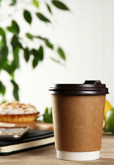 A paper glass with coffee and a notebook on the table