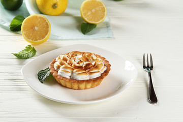 Lemon pie on a plate on a white wooden table