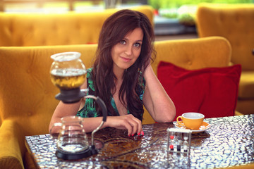 young joyful woman sitting in a cafe and brews green tea