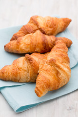 Tasty buttery croissants on old wooden table.