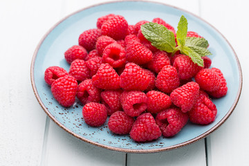 Fresh raspberries in a plate on a  vintage background.