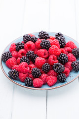 Fresh raspberries in a plate on a  vintage background.
